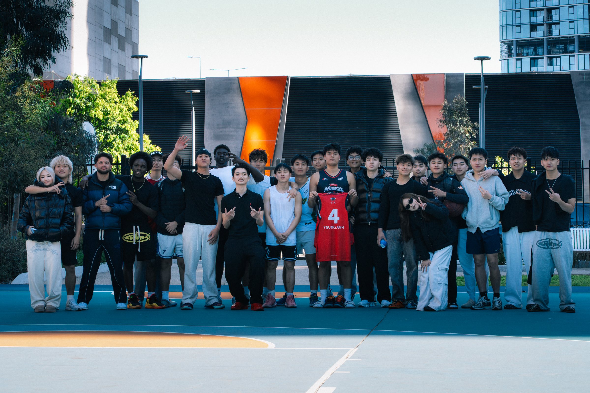 Players and organisers line up for a group photo on an outdoor basketball court