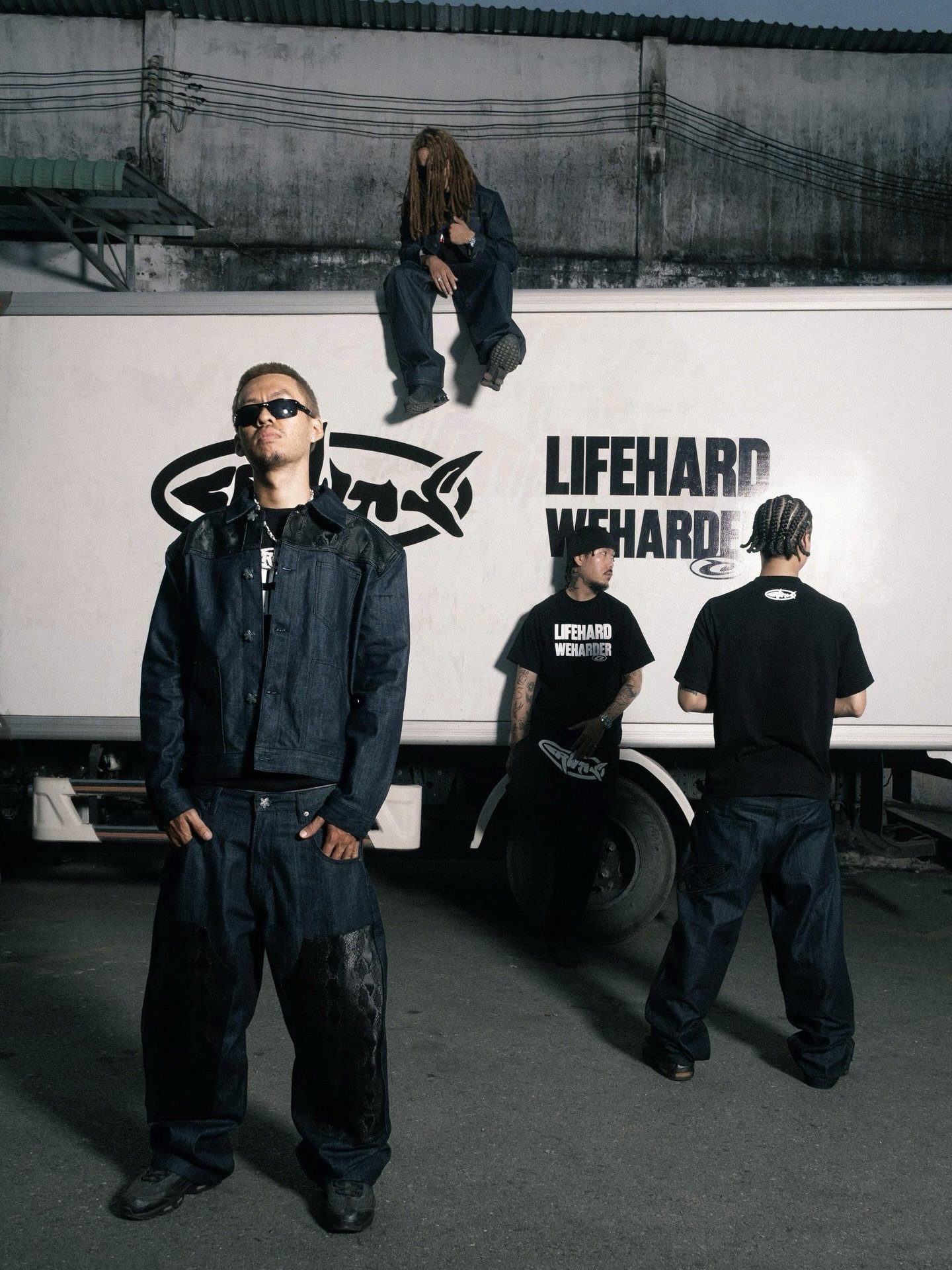 CRUEHAWTS streetwear editorial — four models in dark denim and black tees around a white truck printed “LIFEHARD WEHARDER”